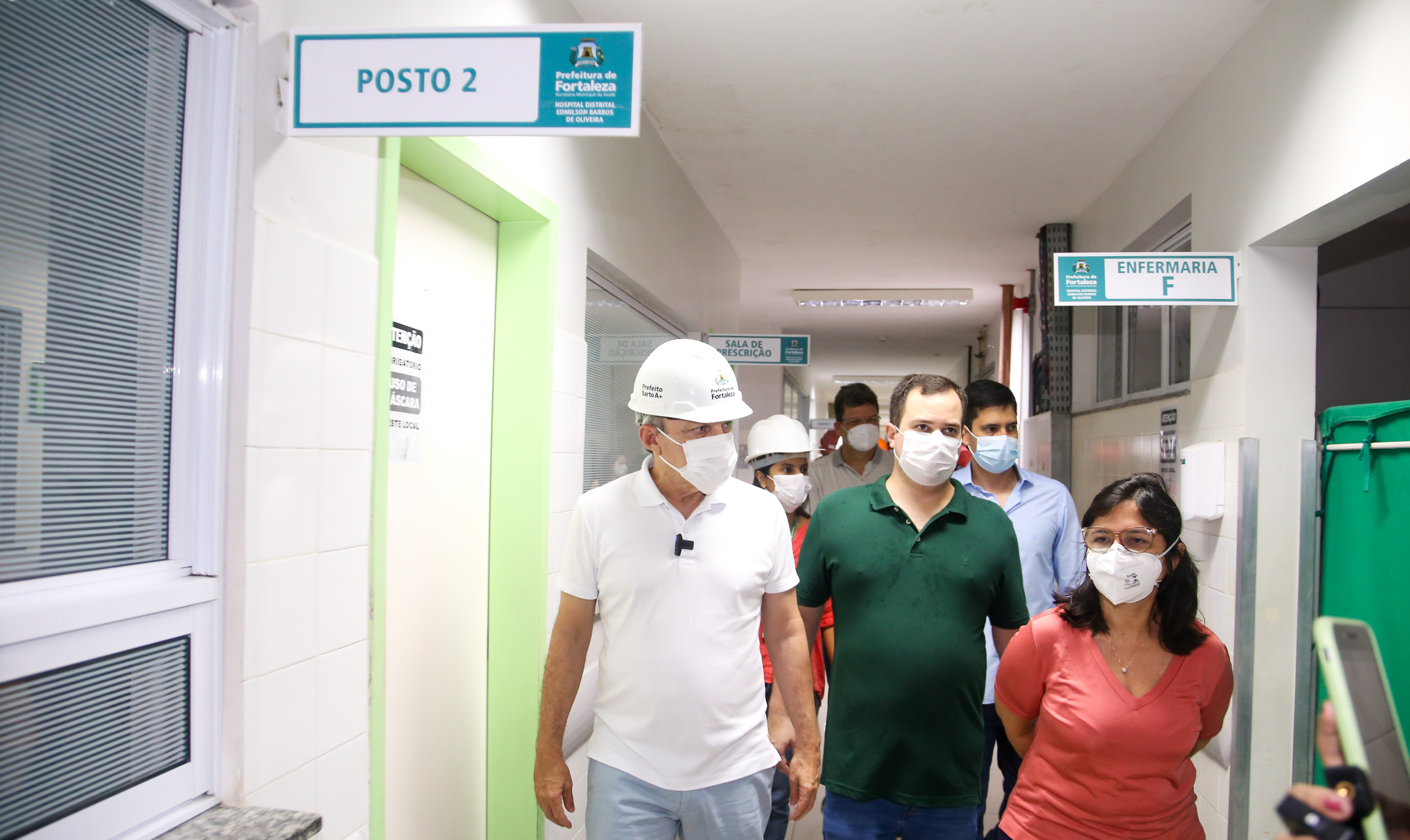 grupo de pessoas com máscara anda em um corredor de hospital